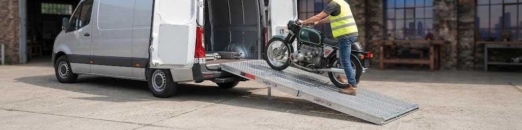 Motorrad wird über zwei Layher U-Alu-Böden als Auffahrrampe in einen Transporter geschoben